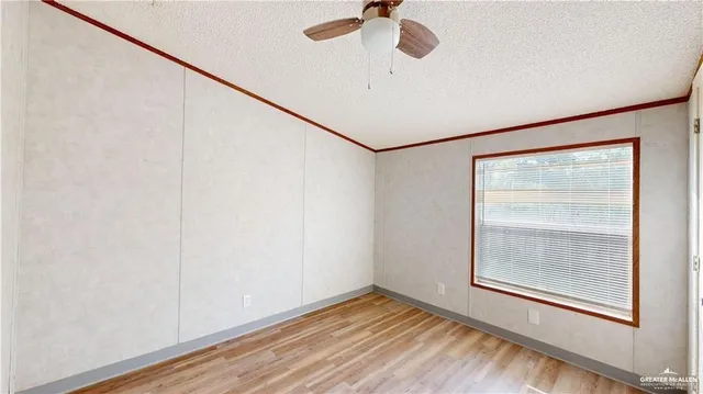 a view of an empty room with a window and wooden floor