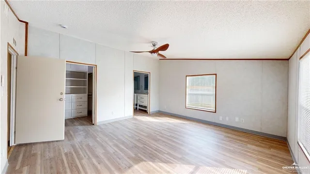 an empty room with wooden floor chandelier fan and windows