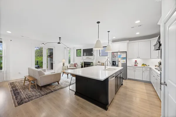 a large white kitchen with a stove a sink dishwasher and a refrigerator with wooden floor