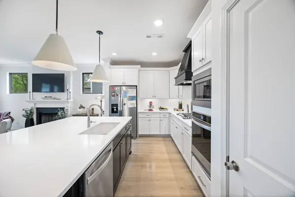 a large kitchen with kitchen island a stove a sink a center island and wooden floor