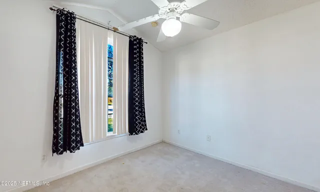 an empty room with windows and chandelier fan