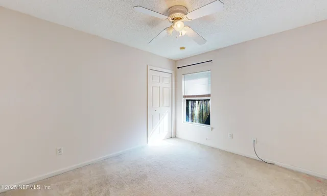 an empty room with a chandelier fan and windows