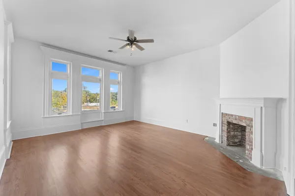 a view of an empty room with a fireplace and a chandelier fan