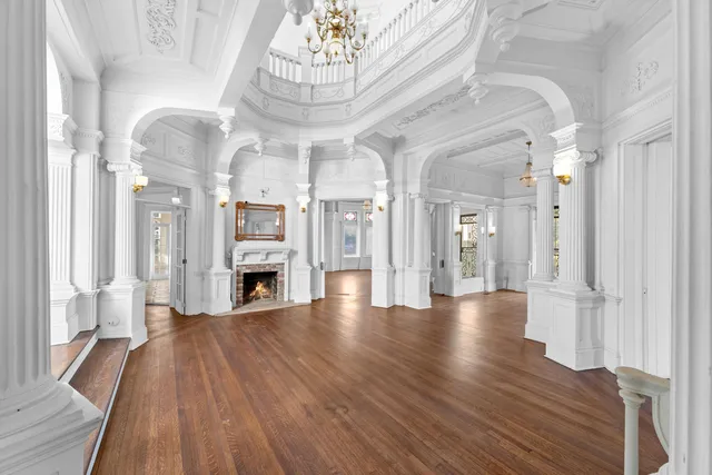 a view of a livingroom with a fireplace a chandelier and wooden floor