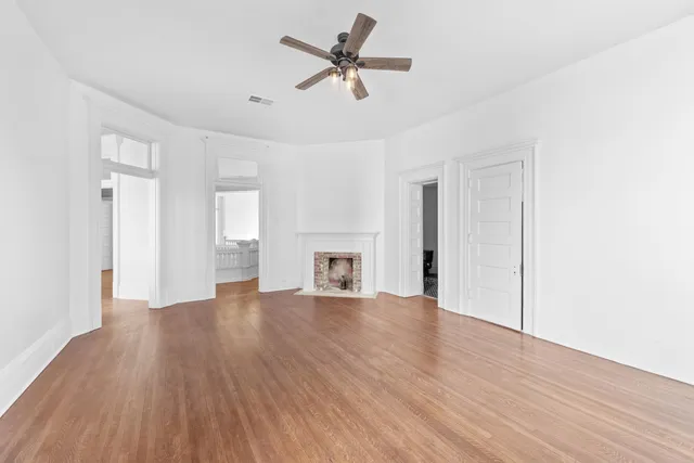 a view of empty room with wooden floor and ceiling fan