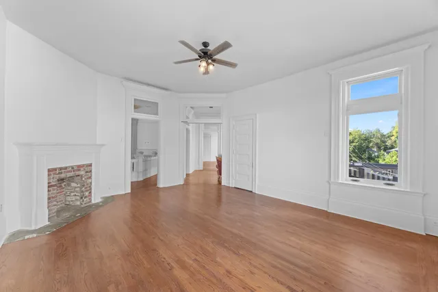 a view of an empty room with a window and wooden floor