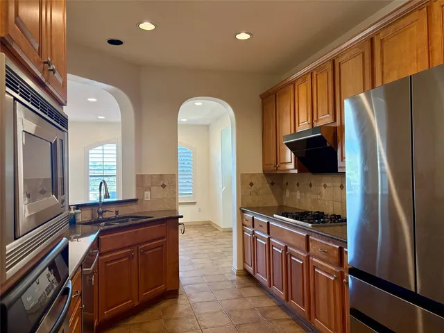 a kitchen with stainless steel appliances granite countertop a refrigerator a stove and a sink