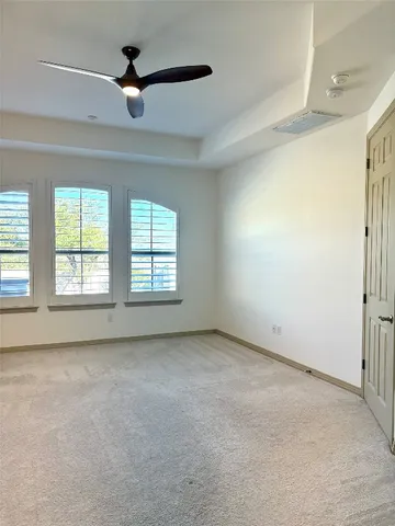 an empty room with windows and fan