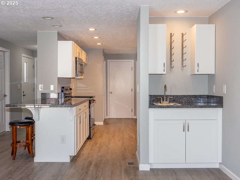 3318 Northeast 29th Street Gresham, OR 97030 - Photo 9 of 32 a kitchen with stainless steel appliances granite countertop a stove a sink and white cabinets with wooden floor