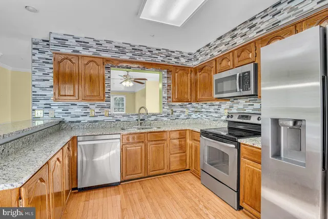 a kitchen with stainless steel appliances granite countertop wooden cabinets and a stove top oven