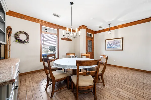 a view of a dining room and livingroom with furniture wooden floor a rug a painting and a chandelier