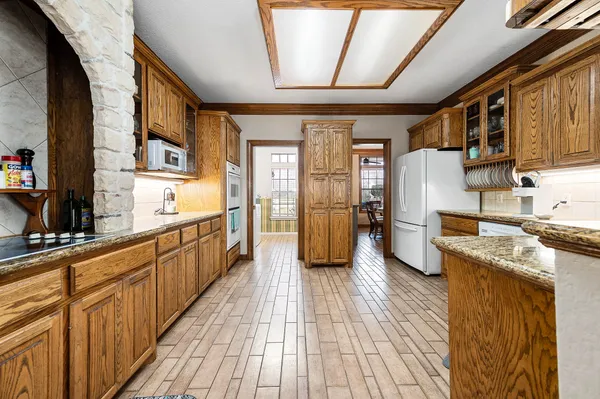 a kitchen with stainless steel appliances granite countertop a refrigerator a sink dishwasher a stove and white countertops with wooden floor