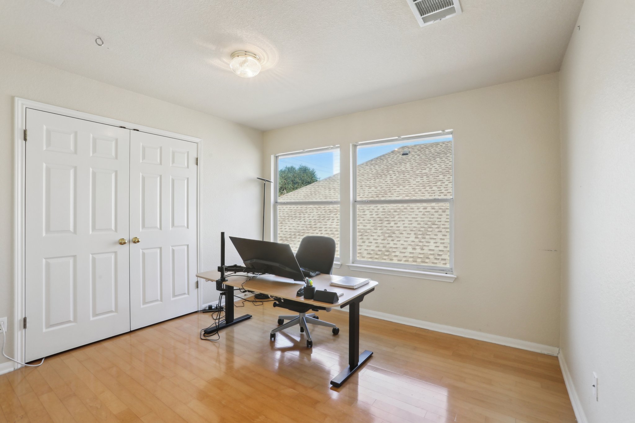 13541 Anarosa Loop Austin, TX 78727 - Photo 20 of 27 Bright room featuring two windows, wood-finish flooring, and a double-door closet with gold-toned hardware