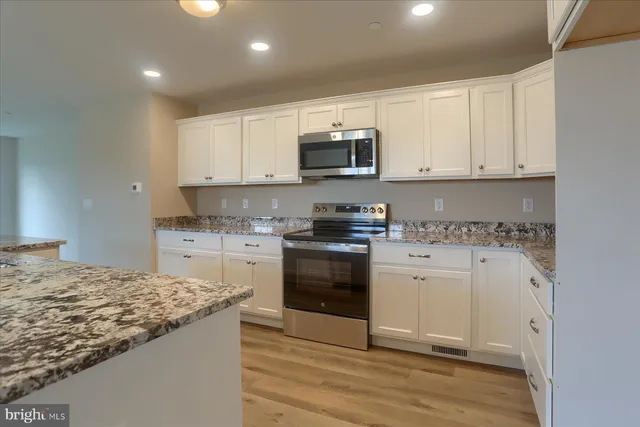 a kitchen with granite countertop white cabinets and stainless steel appliances
