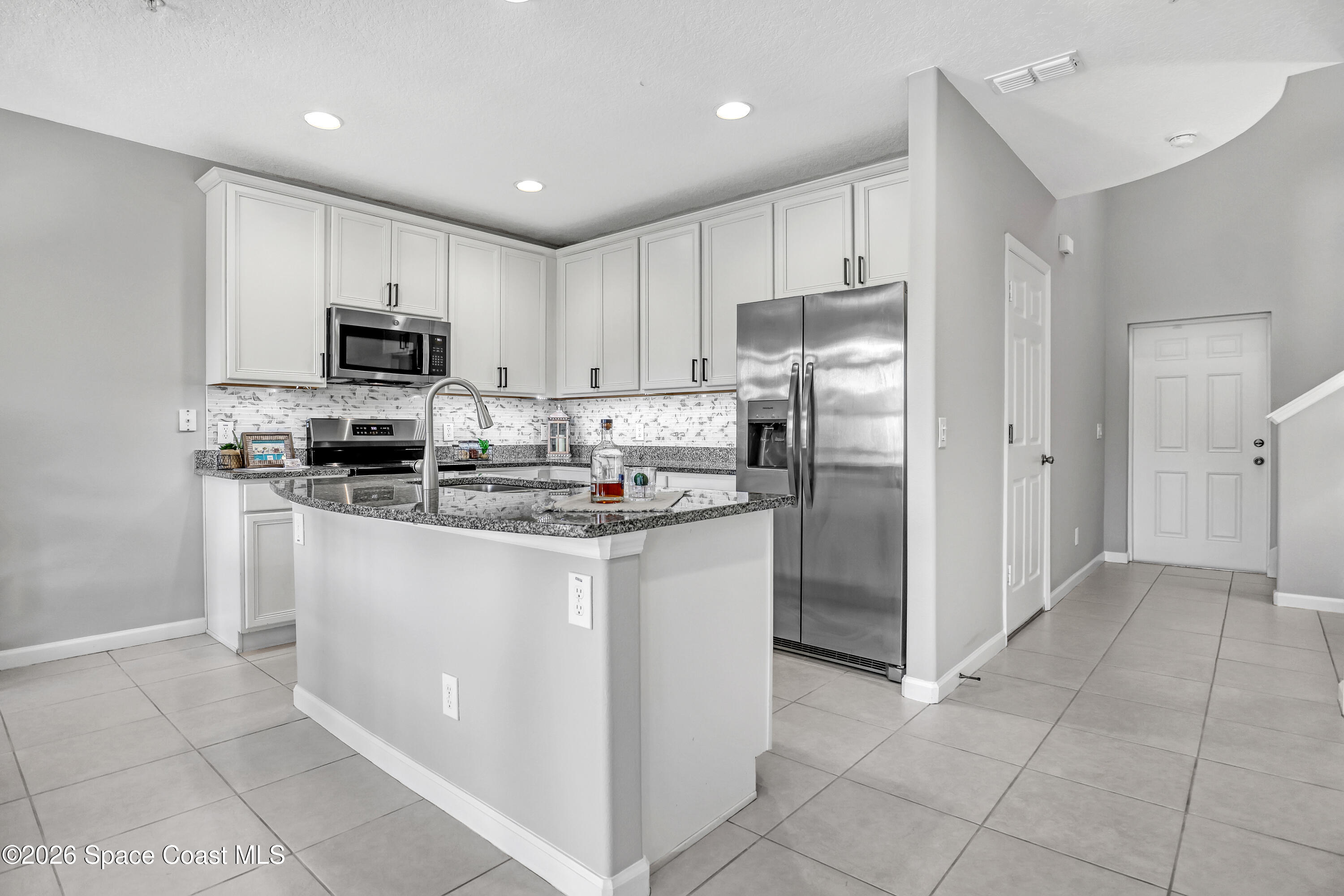 1420 Lara Circle, Unit 102 Rockledge, FL 32955 - Photo 5 of 38 a kitchen with stainless steel appliances granite countertop a refrigerator stove a sink and a microwave