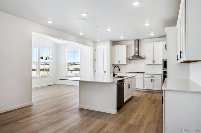 a large kitchen with stainless steel appliances refrigerator a stove top oven and a center island with wooden floor