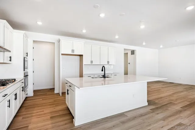 a large white kitchen with wooden floor and a sink