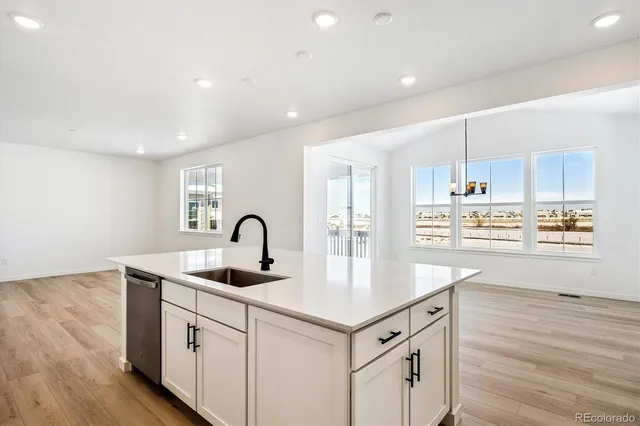 a kitchen with kitchen island granite countertop a sink cabinets and wooden floor