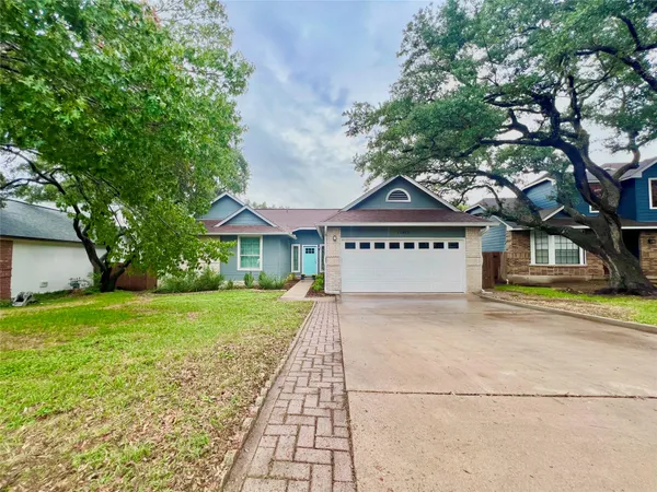 a view of a house with a yard and a large tree