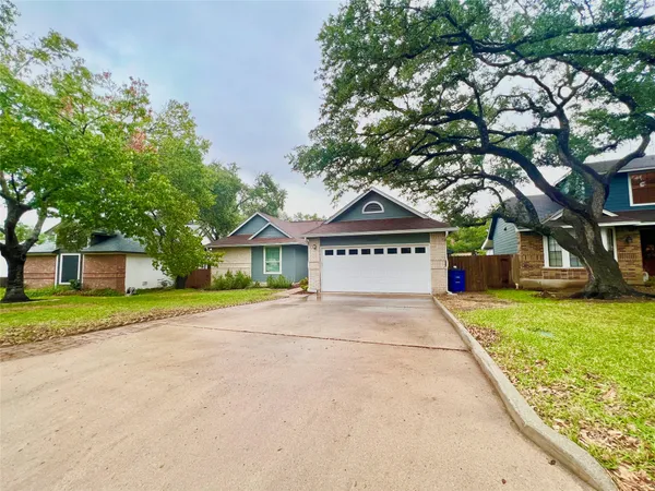 a view of a house with a yard and large trees