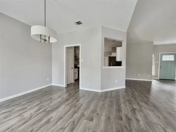 a view of an empty room with wooden floor fireplace and a window