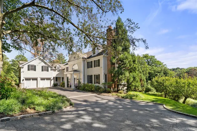a front view of a house with a yard and a tree