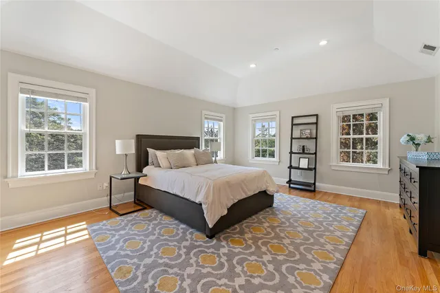 a spacious bedroom with a large bed a rug and two windows