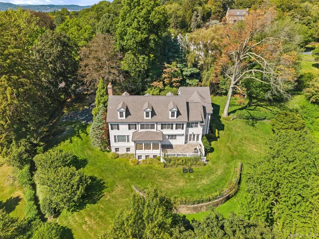 an aerial view of a house with swimming pool and trees