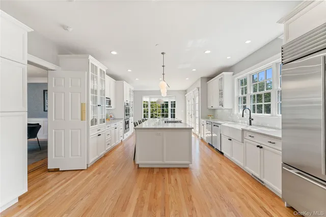 a large kitchen with kitchen island wooden floors wooden cabinets and stainless steel appliances