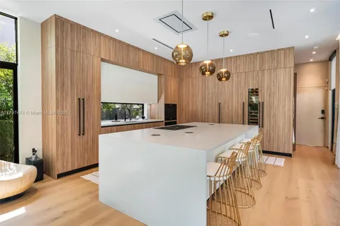 a kitchen with kitchen island a stove a refrigerator and a dining table with wooden floor