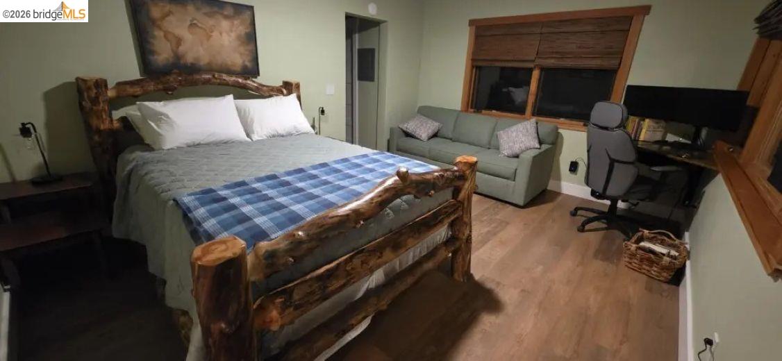 18399 Lime Kiln Road Sonora, CA 95370 - Photo 17 of 36 Bedroom featuring light green walls, wood-finish flooring, and a rustic wood bed frame