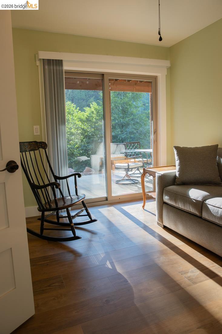 18399 Lime Kiln Road Sonora, CA 95370 - Photo 20 of 36 Sliding glass door leading to an outdoor deck, wood-finish flooring, light green wall paint, and white trim