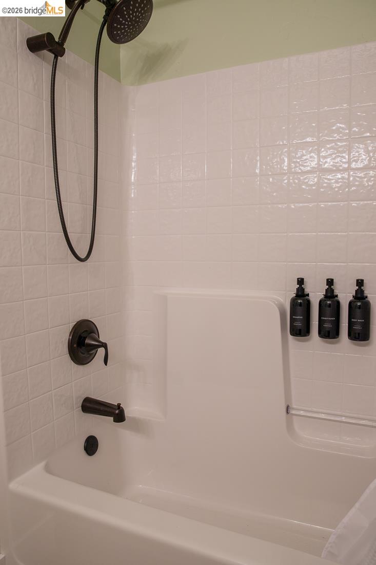 18399 Lime Kiln Road Sonora, CA 95370 - Photo 26 of 36 Bathtub and shower combination featuring white subway tile surround, oil-rubbed bronze fixtures, and an integrated bath ledge