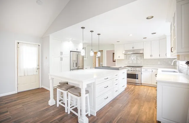 a kitchen with stainless steel appliances sink cabinets and wooden floor