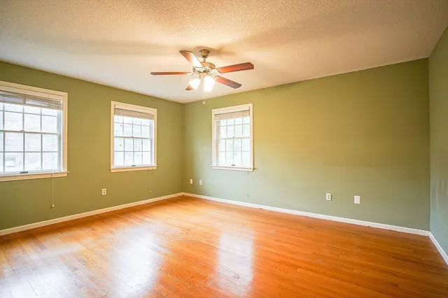 a view of an empty room with window and wooden floor