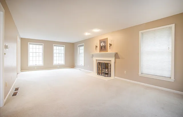 an empty room with windows and fireplace