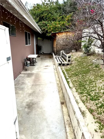 a view of a backyard with chairs and potted plants