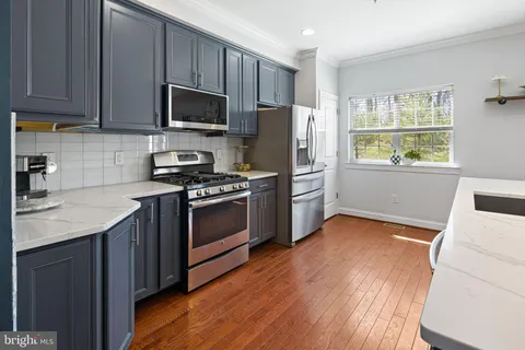 a kitchen with granite countertop wooden floors stainless steel appliances and window