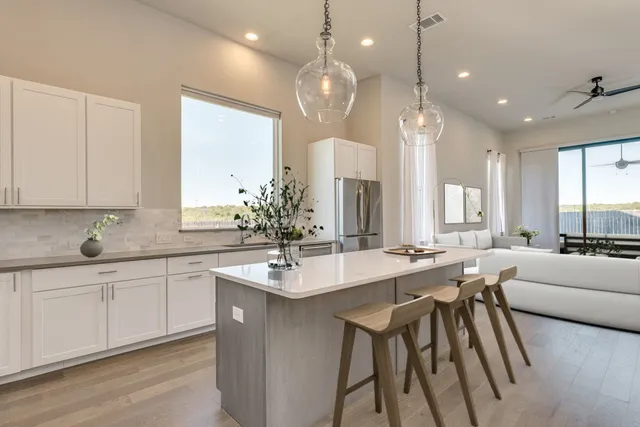 a kitchen with stainless steel appliances granite countertop a sink a stove a refrigerator and island with wooden floor