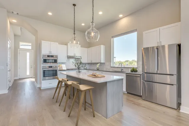 a large white kitchen with a large island oven a stove a dining table and chairs