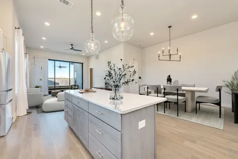a large white kitchen with a large island oven a stove a dining table and chairs