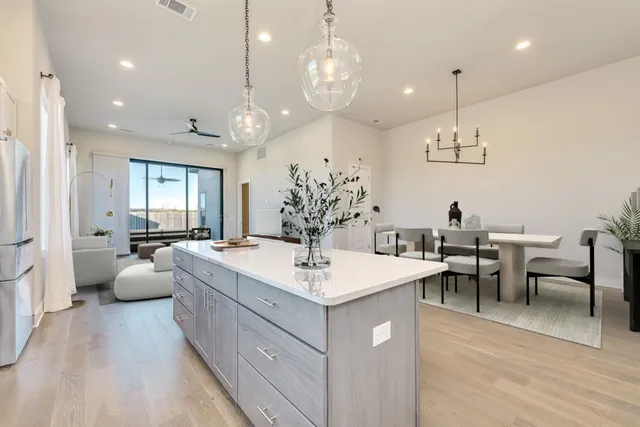 a large white kitchen with a large island oven a stove a dining table and chairs