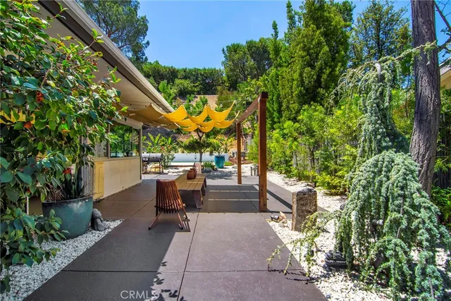 a view of a patio with table and chairs potted plants and large tree