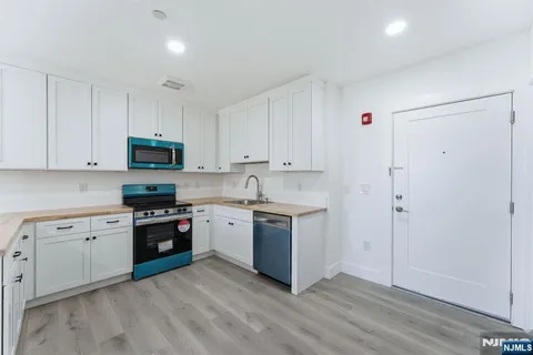 a kitchen with stainless steel appliances granite countertop a stove top oven a sink and dishwasher with white cabinets