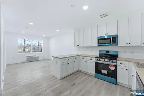 a kitchen with granite countertop white cabinets and black stainless steel appliances