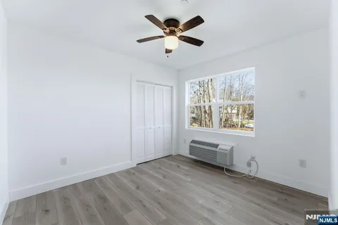an empty room with chandelier fan and windows