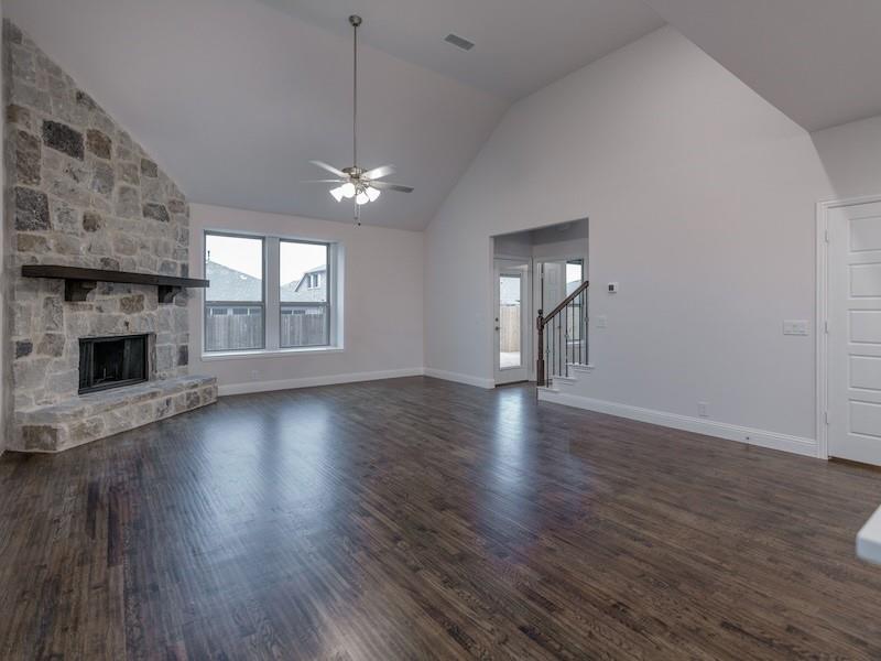 145 Winterwood Drive Lavon, TX 75166 - Photo 11 of 24 Unfurnished living room featuring dark hardwood / wood-style floors, ceiling fan, lofted ceiling, and a stone fireplace