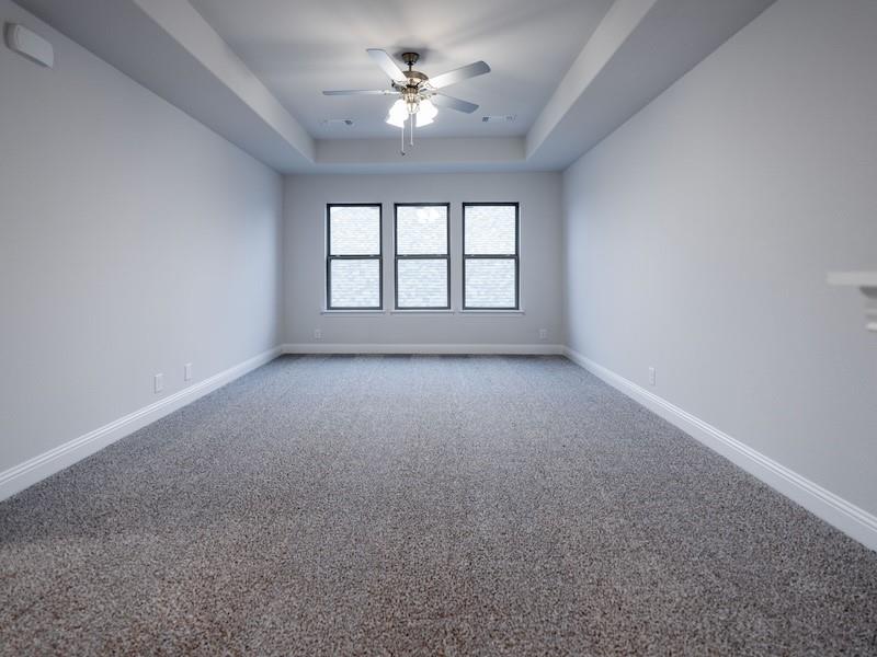 145 Winterwood Drive Lavon, TX 75166 - Photo 22 of 24 Carpeted spare room featuring ceiling fan and a tray ceiling