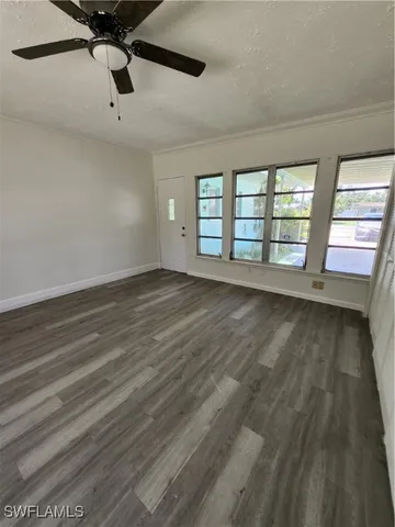 a view of an empty room with a window and wooden floor