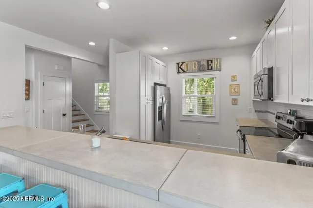 a kitchen with stainless steel appliances white cabinets a sink and a stove